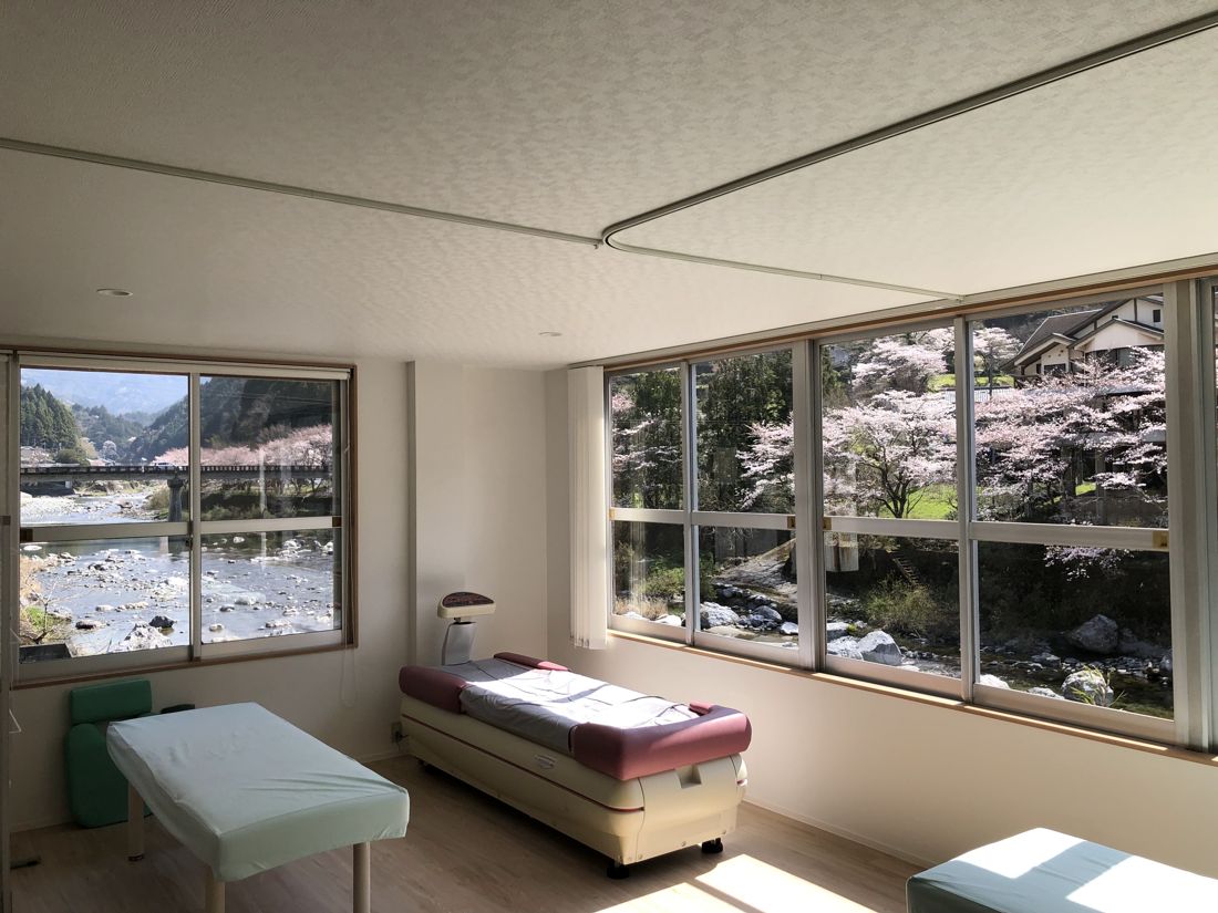 大きな窓から仁淀川と桜並木を望む明るい施術室